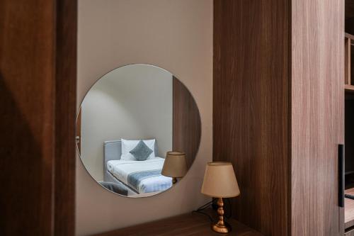 a mirror in a room with a bed and a lamp at Eden Garden Hotel Apartment in Manama