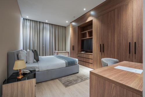 a hotel room with a bed and a desk and a tv at Eden Garden Hotel Apartment in Manama