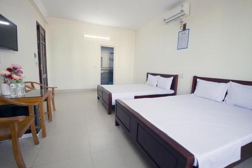 a room with two beds and a table and a chair at Loan Ngạn Hotel Hải Hòa in Nghi Sơn