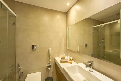 a bathroom with a sink and a toilet and a mirror at The Avenue Regent in Cochin
