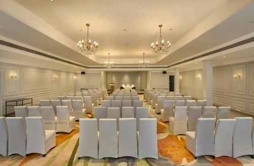 a room with rows of white chairs and chandeliers at The Avenue Regent in Cochin