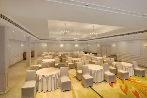 a large room with white tables and white chairs at The Avenue Regent in Cochin