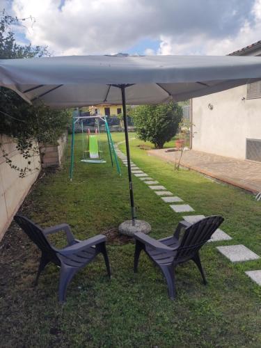 two chairs under an umbrella next to a playground at La tana della Fenice in Labico