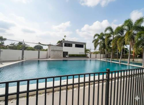 a large swimming pool with a fence and palm trees at DL's crib in Lo-oc
