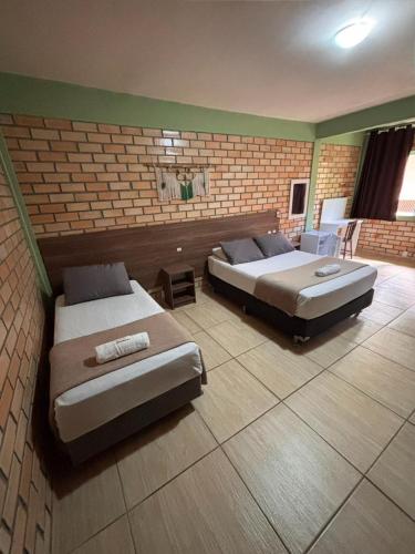 two beds in a room with a brick wall at Pousada Dona Francisca in Florianópolis