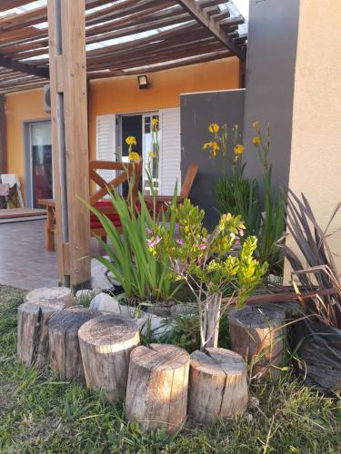 a garden with logs and plants in front of a house at Casa vacaciones Camet Norte in Camet Norte