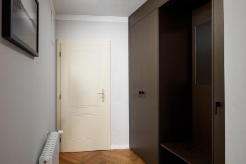 a hallway with a white door and a black closet at The Bridge Residence by Little King in Prague