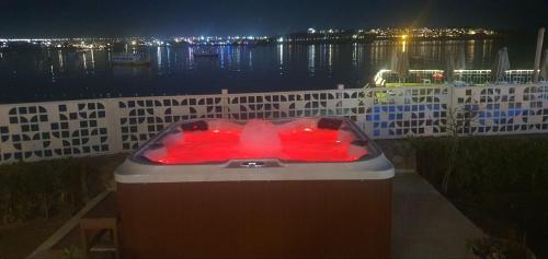 a bath tub with red lights in front of a body of water at Jewel Sharm El Sheikh Hotel in Sharm El Sheikh