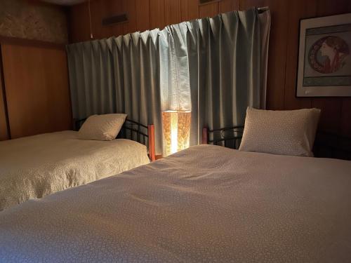 a bedroom with two beds and a window with curtains at Family Resort Apartment in Funabashi