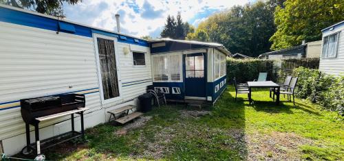 an rv parked in a yard next to a table at Caravane en pleine nature ferme proche de tout in Philippeville