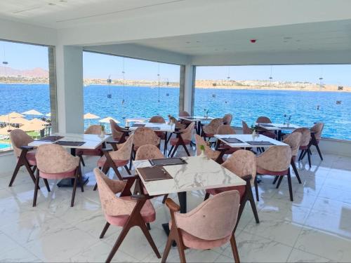 a restaurant with tables and chairs and the water at Jewel Sharm El Sheikh Hotel in Sharm El Sheikh