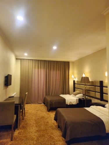 a hotel room with two beds and a desk at GSR INFINITY HOTEL And APARTMENT in Tbilisi City