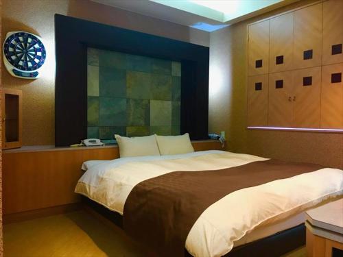 a bedroom with a large bed with a clock on the wall at Hotel Festa (Adult Only) in Narita