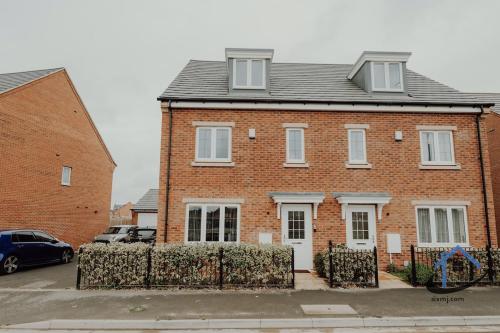 una casa di mattoni con una recinzione di fronte di Moore House 3 bed 3 and half bathroom x2 parking a Market Harborough