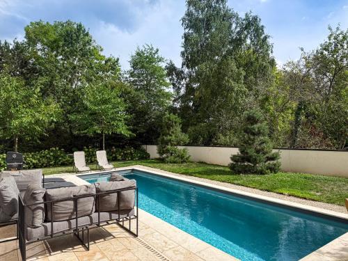 a swimming pool with chairs and a couch next to a pool at Les Trois Cyprès in Blois