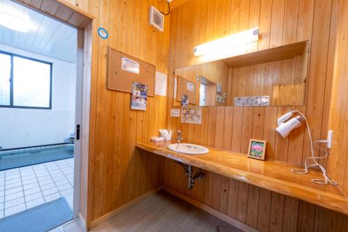 a wooden bathroom with a sink and a mirror at Lodge Matsuya in Nozawa Onsen