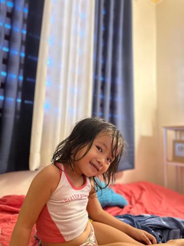 a little girl sitting on top of a bed at Espineli Transient Home in Surigao
