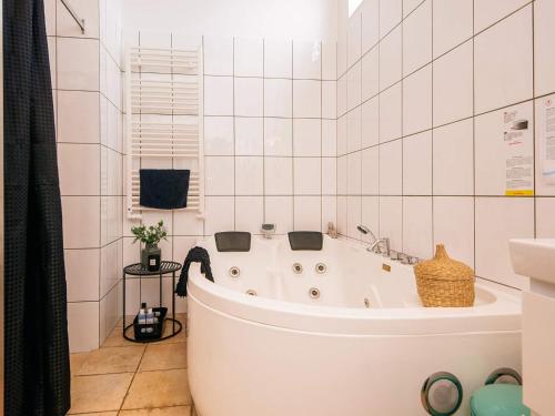a white bath tub in a white tiled bathroom at Exclusive Retreat with Spa - By Traum Ferienwohnungen in Rømø Kirkeby