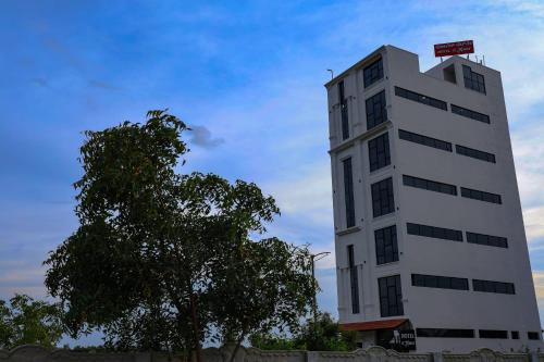 a tall white building with a tree in front of it at Hotel jetway in Muthugadahalli
