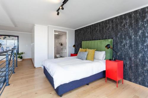 una camera da letto con un letto grande e un comodino rosso di Stylish Cape Town Penthouse a Città del Capo