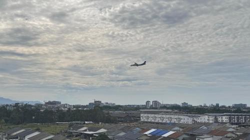 a plane is flying in the sky over buildings at Tiarra星野宿 in Kuching