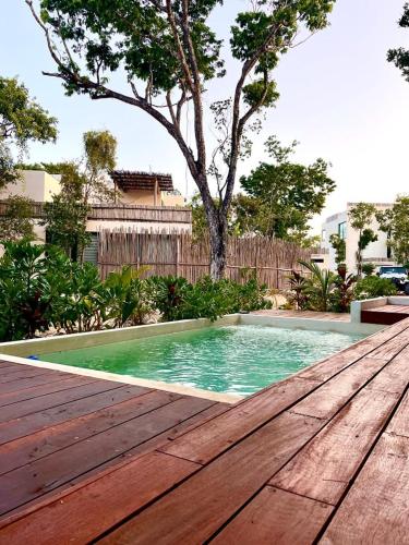 a swimming pool with a wooden deck and a tree at Deluxe Tulum Villa KIIN in Tulum