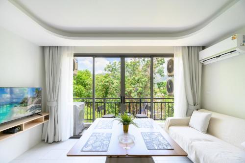 a living room with a white couch and a large window at Fantasea Condo Kamala A503 2BDRM by Phuket Sabay Rent in Kamala Beach