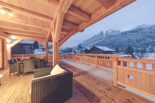 a large wooden deck with chairs and tables on a roof at Chalet La Rocca in La Chapelle-dʼAbondance
