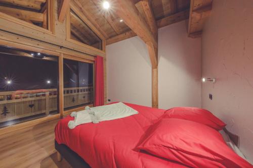 a red bed in a room with a large window at Chalet La Rocca in La Chapelle-dʼAbondance