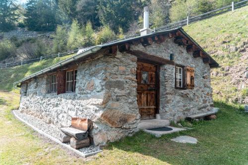 a stone house with a bench in front of it at Idyllisches und alleinstehendes Maiensäss in Valposchiavo in Poschiavo