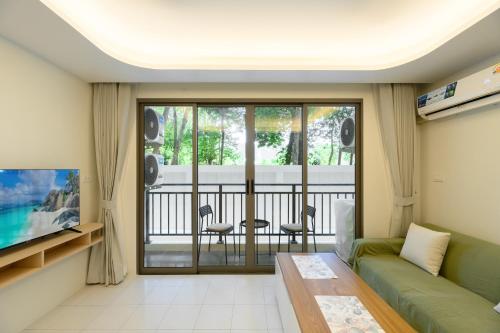 a living room with a green couch and a balcony at Fantasea Condo Kamala B211 2BDRM by Phuket Sabay Rent in Kamala Beach