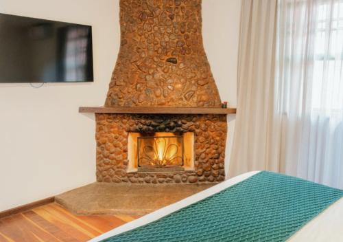 a stone fireplace in a room with a bed at Kastel Pedra Bonita in Petrópolis