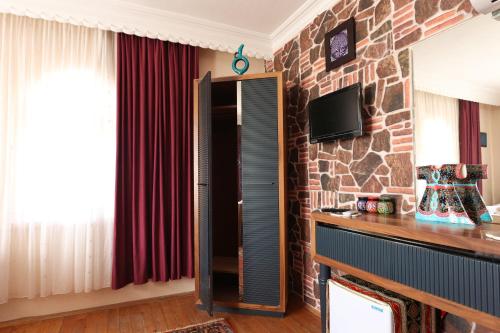 a living room with a stone wall with a tv and a cabinet at Cappadocia Hostel in Goreme