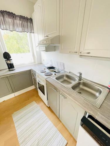a white kitchen with a sink and a stove at Hotelli Aatto&Elli in Joutsa