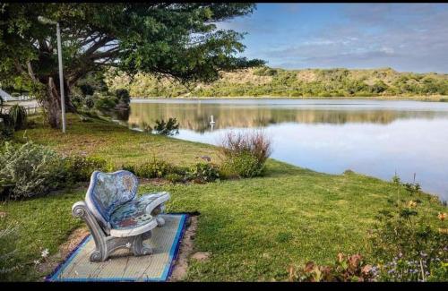 a chair sitting on the grass next to a lake at Ria's Rest Self Catering Flatlet in Sedgefield
