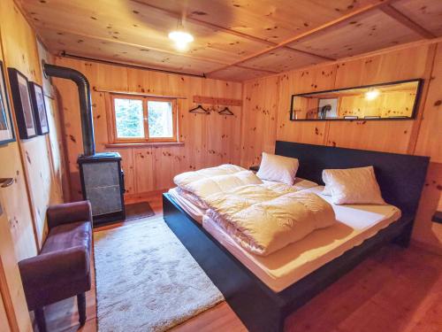 a bed in a wooden room with a stove at Idyllisches und alleinstehendes Maiensäss in Valposchiavo in Poschiavo