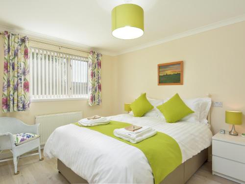 a bedroom with a large bed with green and white sheets at Westburn in Comrie