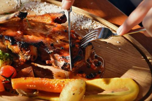a person cutting a plate of food with a fork and knife at Hotel & Restaurant Mulliri me Erë in Rahovec
