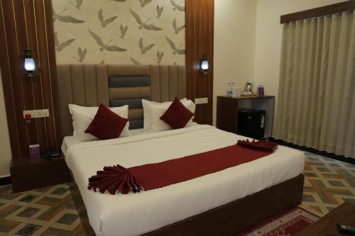 a bedroom with a large bed with red pillows at VITS Select Diamond Resort Sasan Gir in Talala