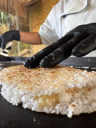 a person wearing black gloves preparing food on a grill at Pousada Império do Sol in Pipa