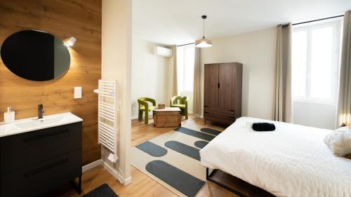 a bedroom with a bed and a sink and a mirror at La Loulove - Nid cosy & design au cœur de Lauzerte in Lauzerte