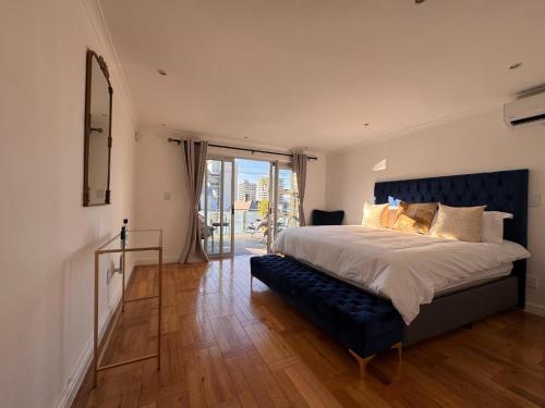 a bedroom with a large bed with a blue headboard at Urban Oasis Penthouse-Jacuzzi! in Cape Town