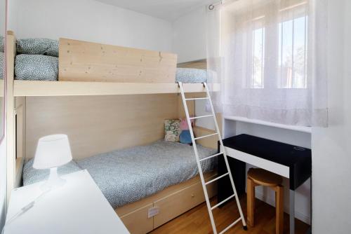 a small bedroom with bunk beds and a desk at Ciasa de Lucky in Moena
