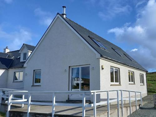 a white house with a bench in front of it at Hirta Cottage in Staffin