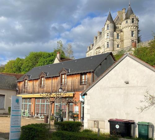 a large building in front of a building with a castle at Le Moulin de la Doltière in Châteauvieux