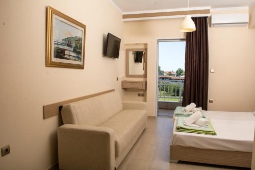 a hotel room with a couch and a bed and a window at Sun Studios Pieria in Paralía Skotínis