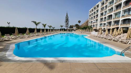 a swimming pool with lounge chairs and a hotel at Cura Marina Premium in Mogán