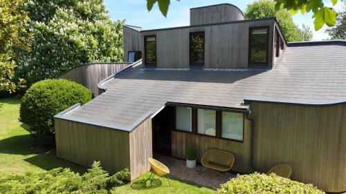 a house with a pitched roof with chairs in the yard at Unique & Rural Child Friendly Annexe with Large Gardens, Games & Tennis Court - Chichester Holiday Properties in Chichester