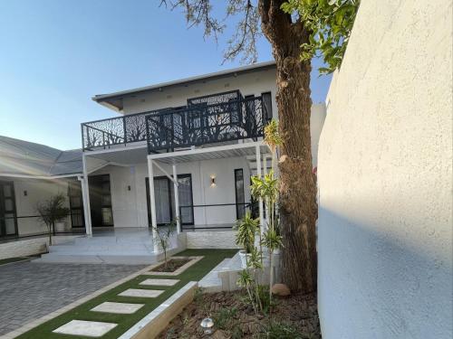 a white house with a tree in front of it at The Amaryllis Guest House in Mariental