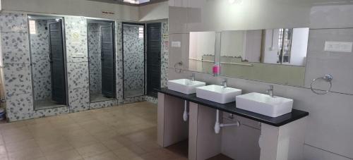 a bathroom with two sinks and a mirror at V R S Luxury AC Male Dormitory in Mysore